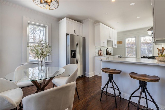 kitchen featuring a healthy amount of sunlight, backsplash, stainless steel fridge, and white cabinets