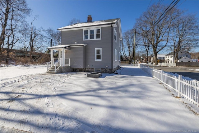 snow covered back of property featuring a fire pit