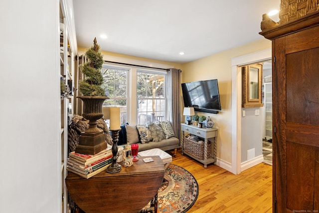living area with baseboards, light wood finished floors, and recessed lighting