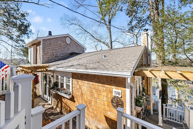 view of side of home with a chimney and a shingled roof