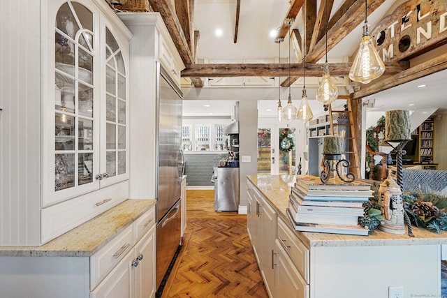 kitchen featuring built in refrigerator, pendant lighting, white cabinetry, and glass insert cabinets