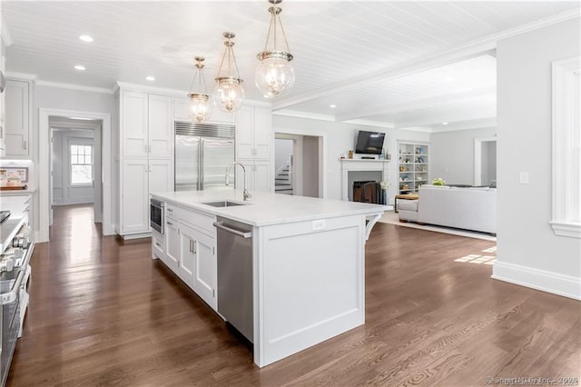 kitchen featuring sink, appliances with stainless steel finishes, white cabinetry, a center island with sink, and decorative light fixtures