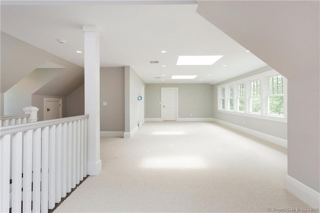 additional living space with a skylight and light colored carpet