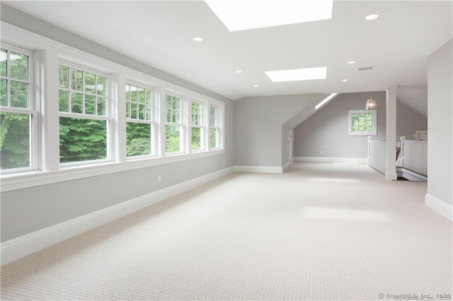 additional living space with vaulted ceiling with skylight and light colored carpet