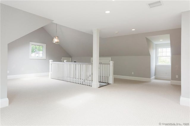 additional living space with lofted ceiling, a healthy amount of sunlight, and light carpet