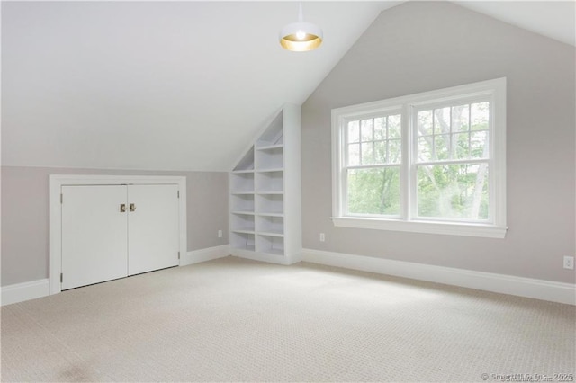 additional living space featuring vaulted ceiling, light carpet, and built in features