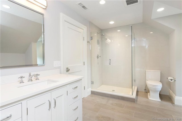 bathroom with a shower with door, vanity, and toilet