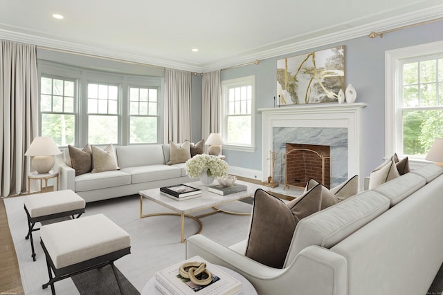 living room with a premium fireplace, crown molding, and plenty of natural light