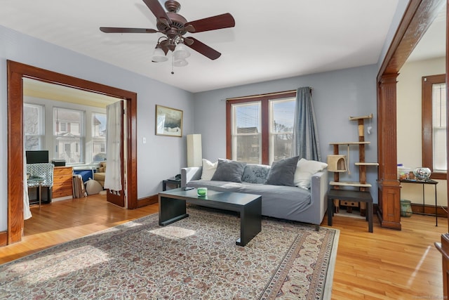 living room with ceiling fan, baseboards, and wood finished floors