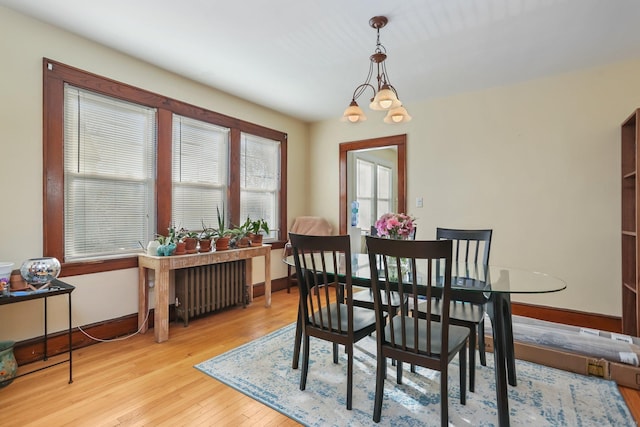 dining room featuring baseboards, radiator heating unit, light wood-type flooring, and an inviting chandelier