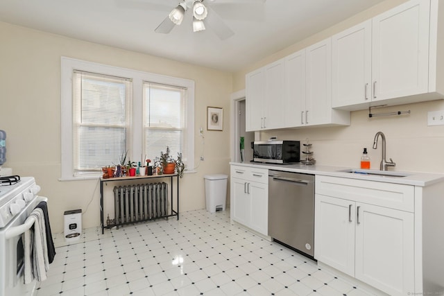 kitchen featuring stainless steel appliances, radiator, light countertops, white cabinetry, and a sink