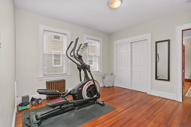 exercise room featuring radiator heating unit, wood finished floors, and baseboards