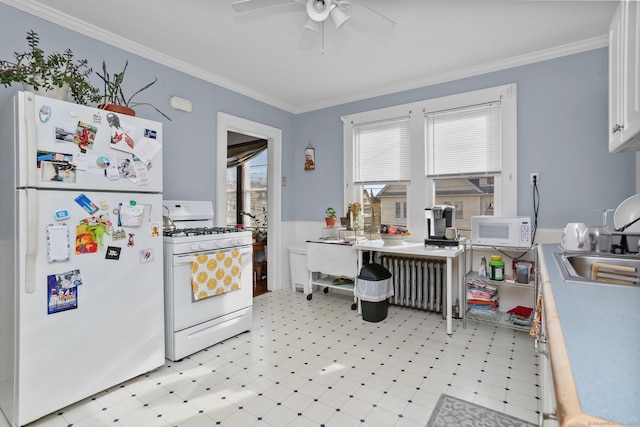 kitchen featuring white appliances, radiator heating unit, white cabinetry, and light floors