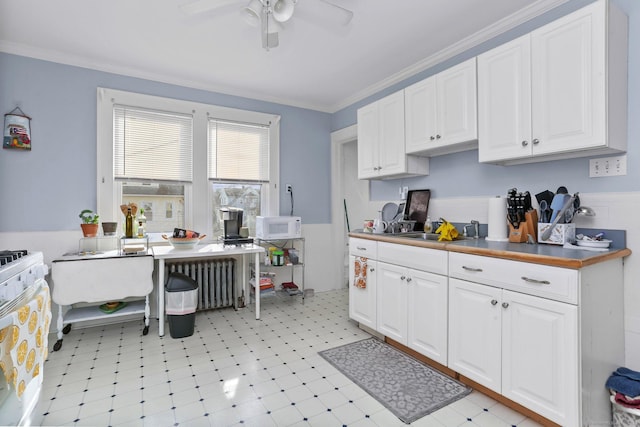 kitchen with white appliances, radiator heating unit, white cabinetry, and ornamental molding