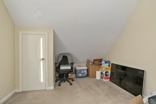 office area with baseboards, vaulted ceiling, and light colored carpet