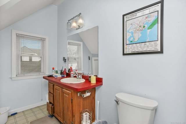 bathroom featuring baseboards, toilet, tile patterned floors, vaulted ceiling, and vanity