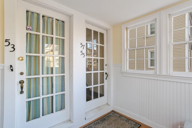 doorway to outside with a wainscoted wall