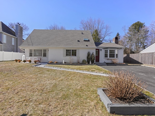 back of house featuring roof with shingles, fence, a chimney, and a lawn