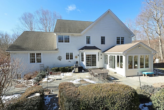 snow covered rear of property with a sunroom and a patio area