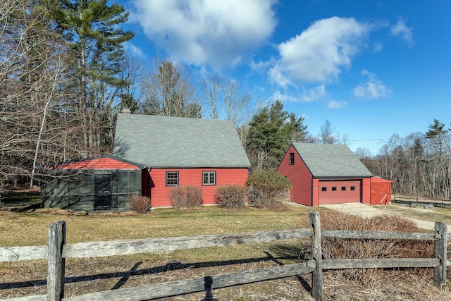 view of front of home with an outbuilding, fence, driveway, a garage, and a chimney