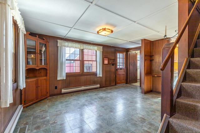 foyer with coffered ceiling, a baseboard radiator, wood walls, and stairway