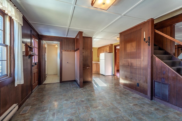 interior space featuring stairs, visible vents, a baseboard heating unit, and wood walls