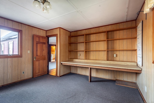 unfurnished office with carpet flooring, wood walls, and a chandelier