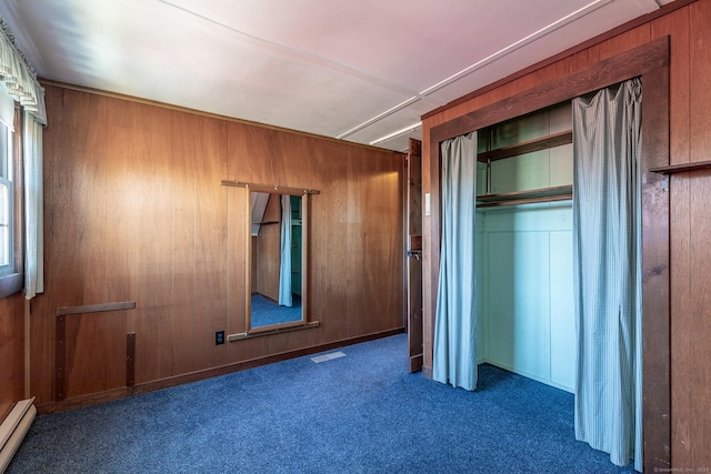 unfurnished bedroom featuring a closet, wood walls, visible vents, carpet, and a baseboard radiator