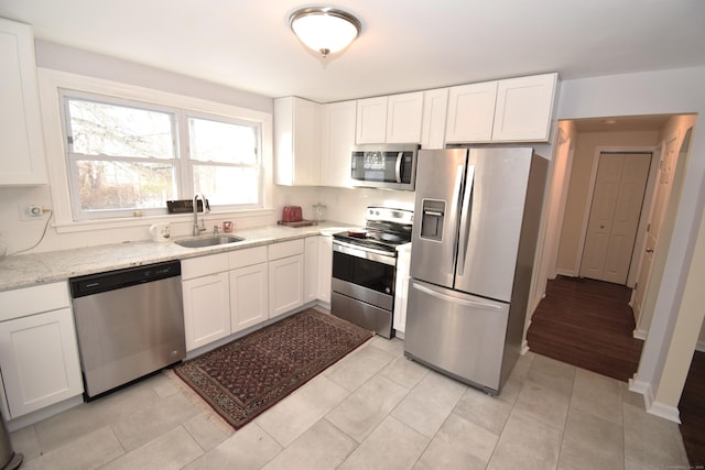 kitchen featuring sink, light stone counters, white cabinets, stainless steel appliances, and backsplash