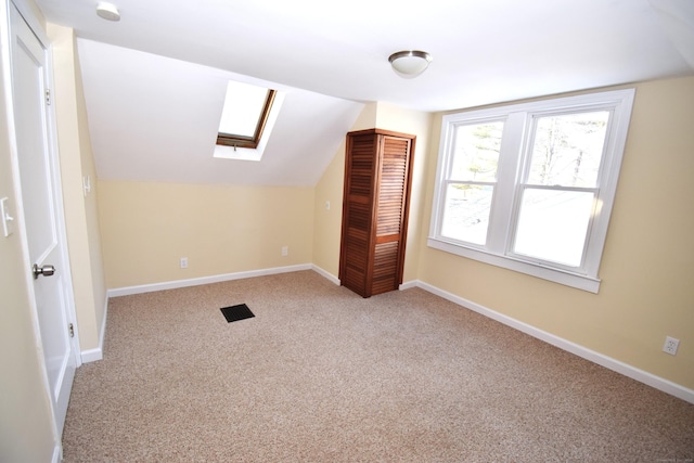 bonus room featuring light colored carpet and vaulted ceiling with skylight