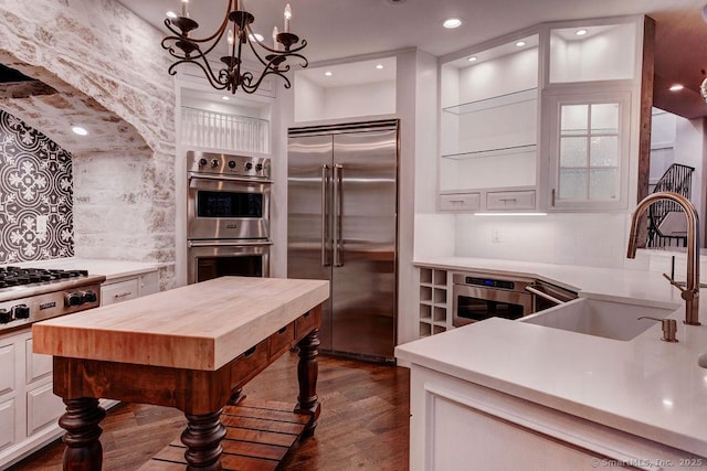 kitchen with sink, dark wood-type flooring, white cabinetry, backsplash, and stainless steel appliances