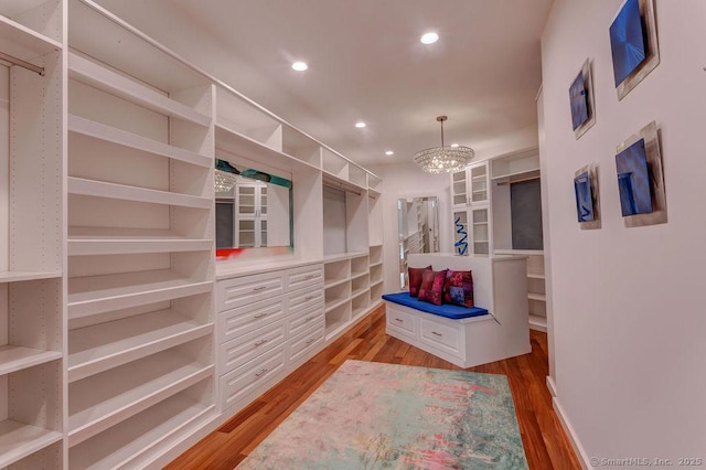 spacious closet with an inviting chandelier and light wood-type flooring