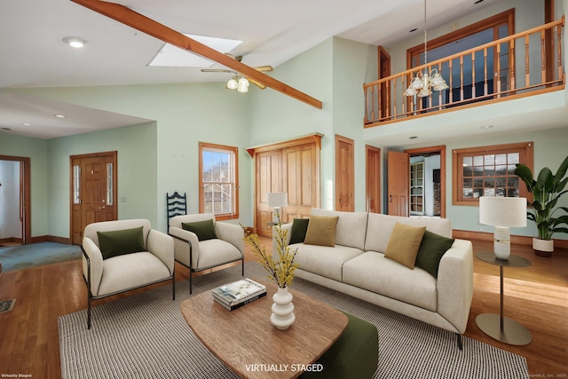 living room featuring hardwood / wood-style flooring, a skylight, and high vaulted ceiling