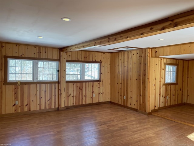 spare room featuring beamed ceiling, wood-type flooring, and plenty of natural light