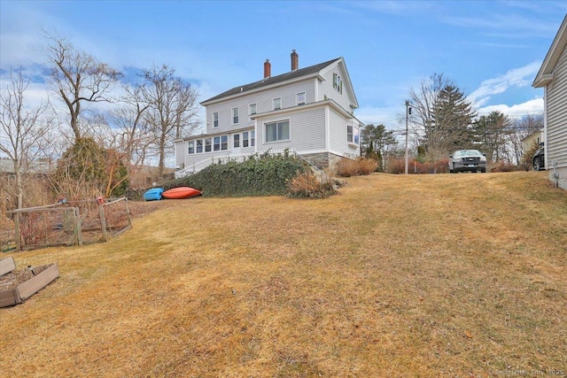 rear view of house featuring a chimney and a lawn