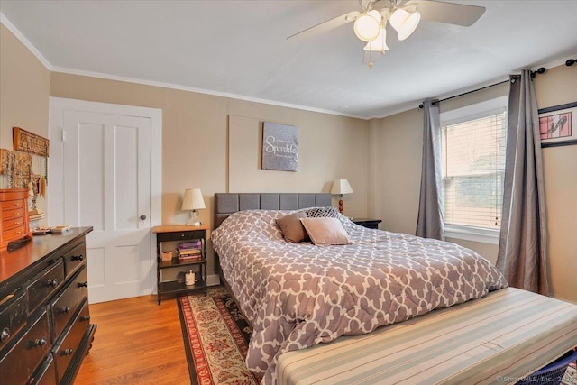 bedroom featuring ornamental molding, light wood-type flooring, and a ceiling fan