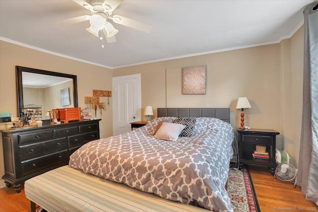 bedroom featuring a ceiling fan, ornamental molding, and wood finished floors