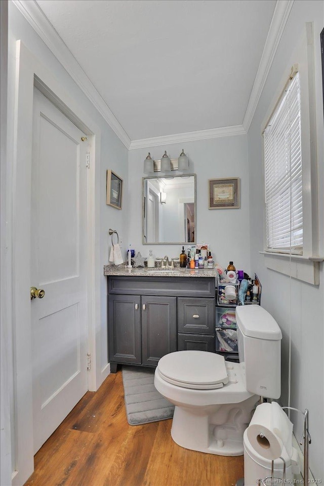 bathroom with toilet, wood finished floors, vanity, and crown molding