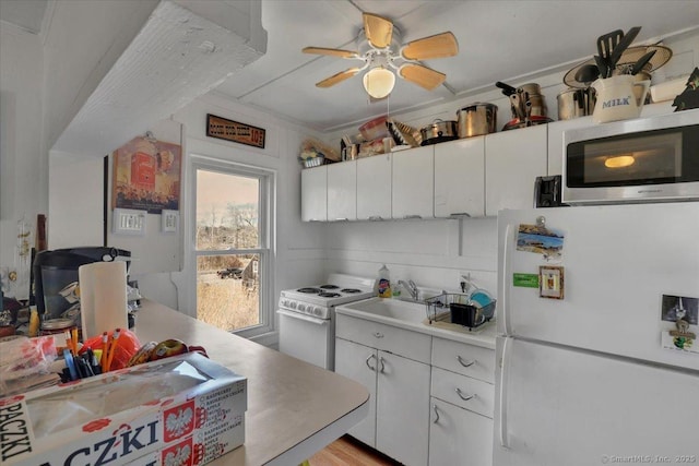 kitchen featuring a ceiling fan, light countertops, white appliances, and white cabinetry