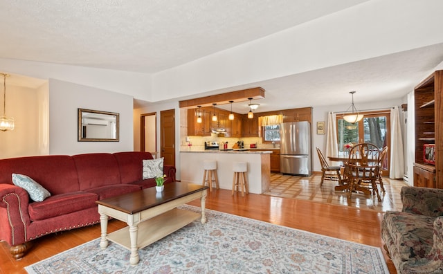 living room with a textured ceiling, a notable chandelier, and light hardwood / wood-style flooring