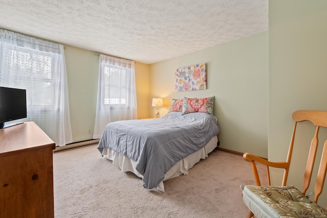 carpeted bedroom with a textured ceiling and a baseboard heating unit