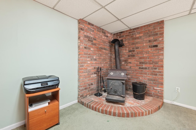 room details featuring carpet, a wood stove, and a drop ceiling