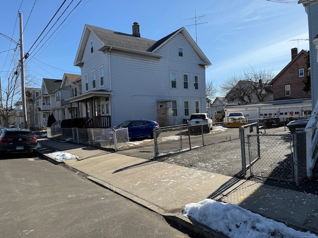 view of side of home with a fenced front yard, a gate, and a chimney