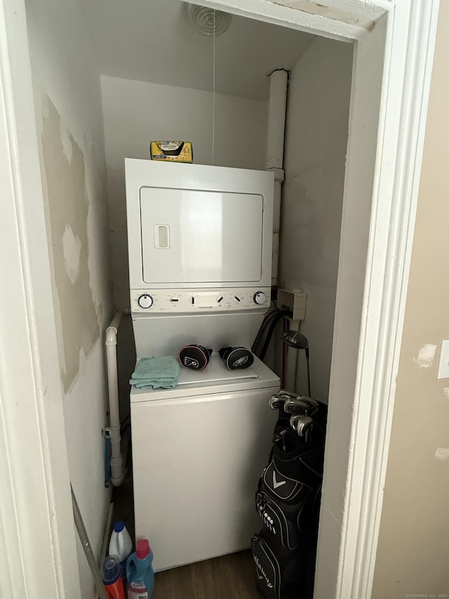 laundry area featuring laundry area, stacked washer and dryer, and wood finished floors