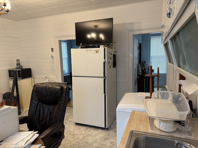 kitchen with black microwave, crown molding, a sink, freestanding refrigerator, and light floors