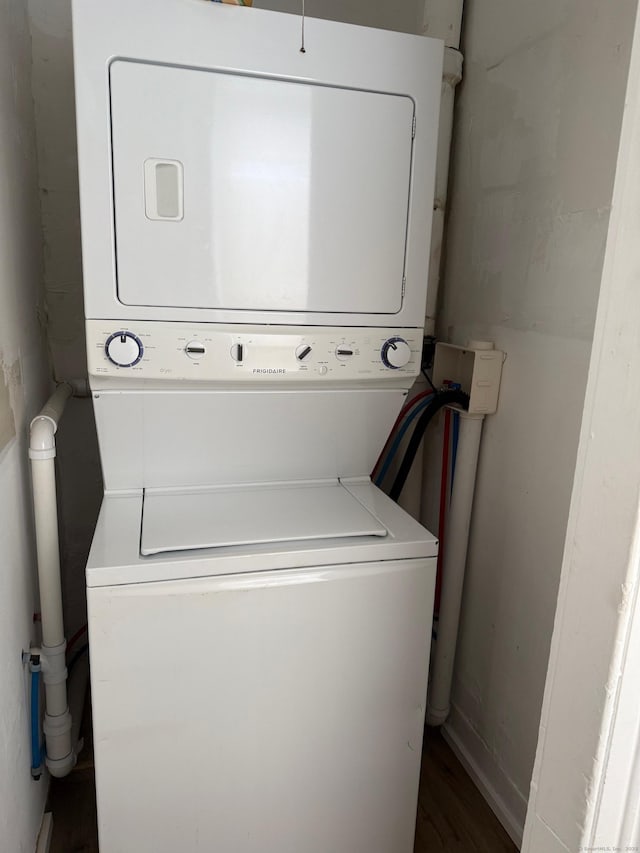 laundry area with laundry area, stacked washer / dryer, and wood finished floors
