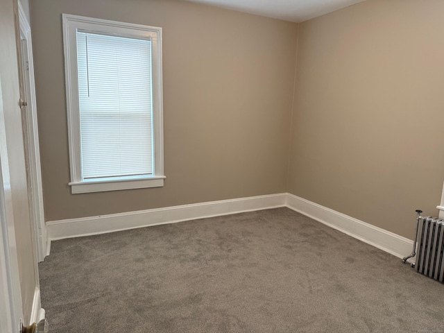 empty room with carpet floors, baseboards, and radiator
