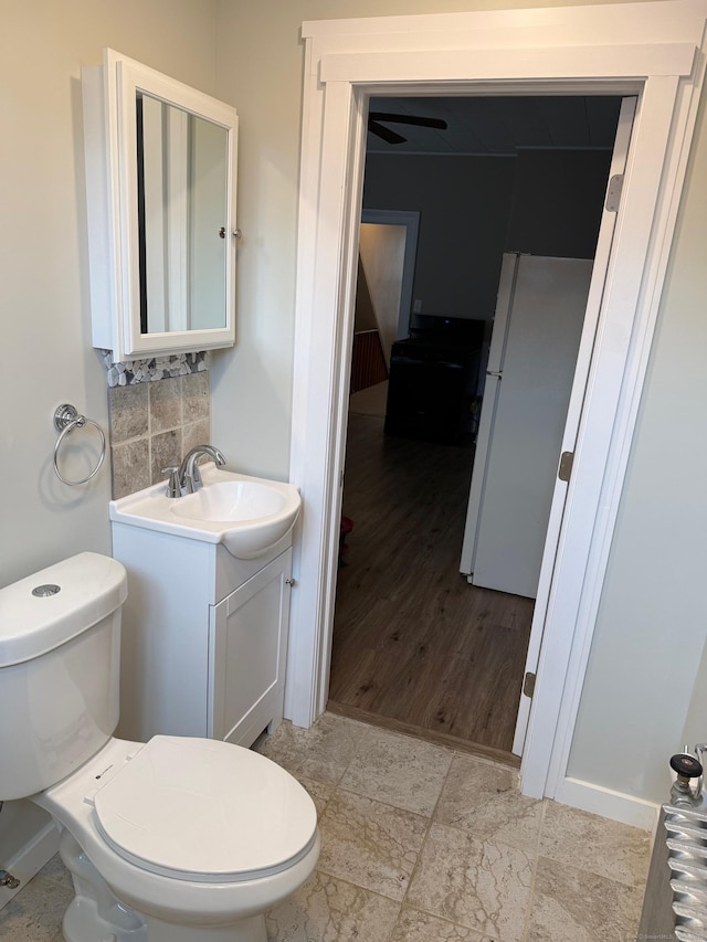 half bath featuring toilet, tasteful backsplash, and vanity