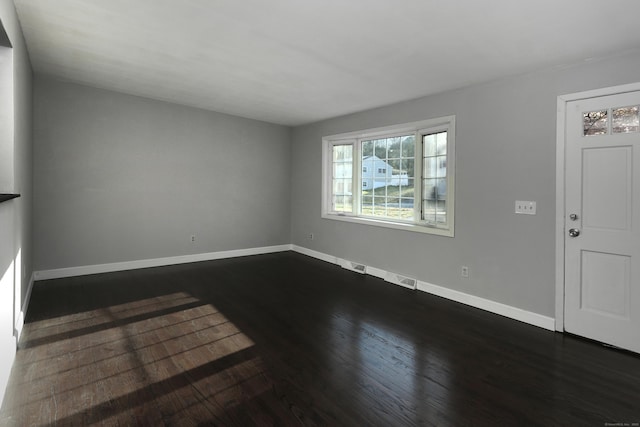 spare room featuring baseboards and dark wood-style flooring