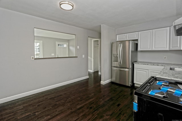 kitchen featuring dark hardwood / wood-style floors, black range oven, white cabinets, stainless steel fridge, and light stone counters